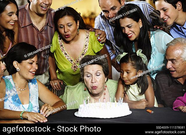 Senior woman blowing out the candles on her birthday cake