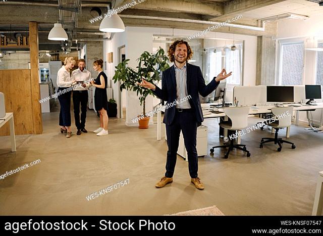 Happy businessman in office with colleagues in background