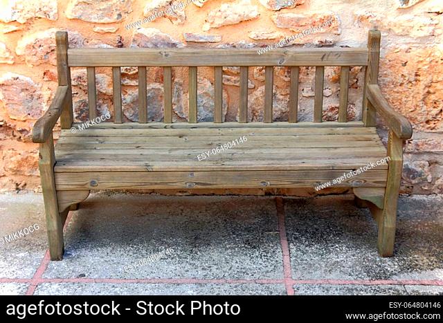 old wooden weathered bench near stone wall