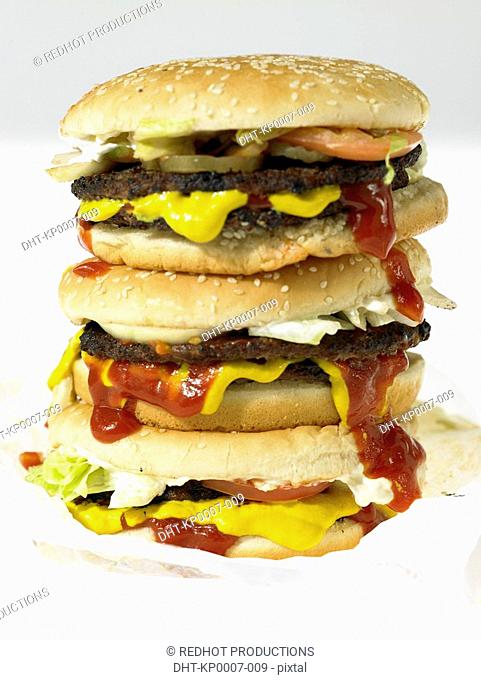 Three beef burgers with toppings in take out packaging