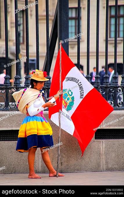 Local woman standing with a flag during Festival of the Virgin de la Candelaria in Lima, Peru. The core of the festival is dancing and music performed by...