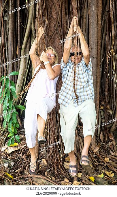 Older, mature couple , retired, playing tarza and jane hanging, having fun hanguing from a tree, and walking hand in hand in a distillery