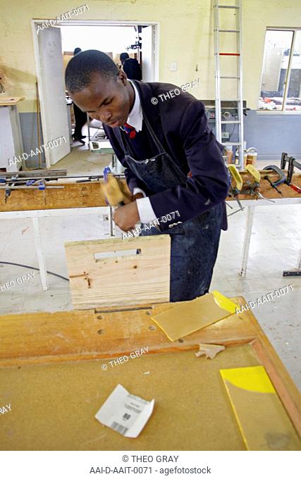School boy chiselling with hammer in woodwork classroom, St Mark's School, Mbabane, Hhohho, Kingdom of Swaziland