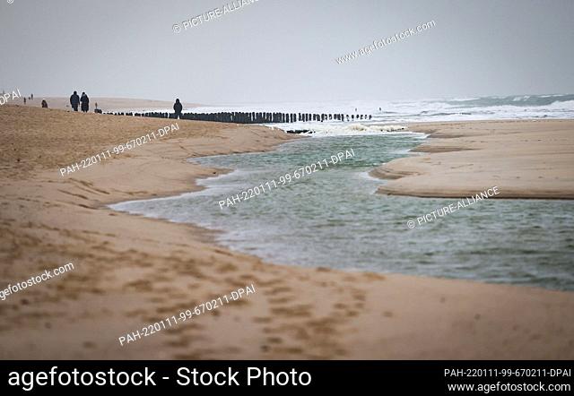 11 January 2022, Schleswig-Holstein, Westerland: Tourists walk on the beach near Westerland on the North Sea island of Sylt