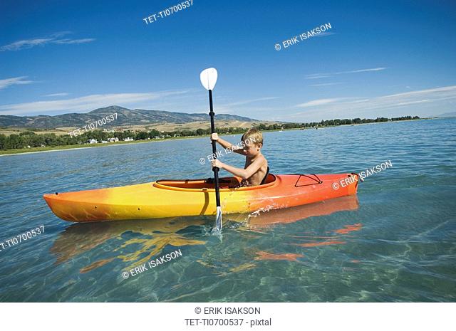 Boy paddling in canoe on lake, Utah, United States