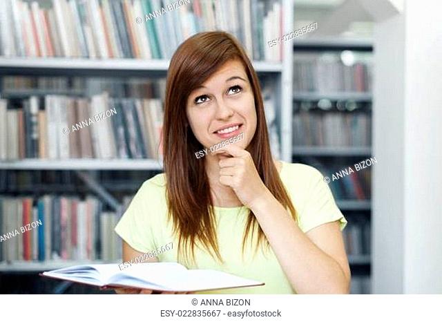 Young woman daydreaming in library