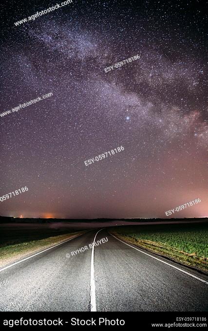 Magenta Night Starry Sky Above Country Asphalt Road In Countryside And Green Field. Night View Of Natural Glowing Stars And Milky Way Galaxy