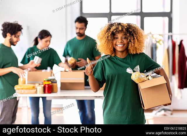 female volunteer with food in box shows thumbs up