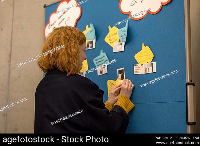21 January 2023, Saxony, Dresden: A woman puts a piece of paper on a flipchart at the state conference of various organizations for Ukraine aid