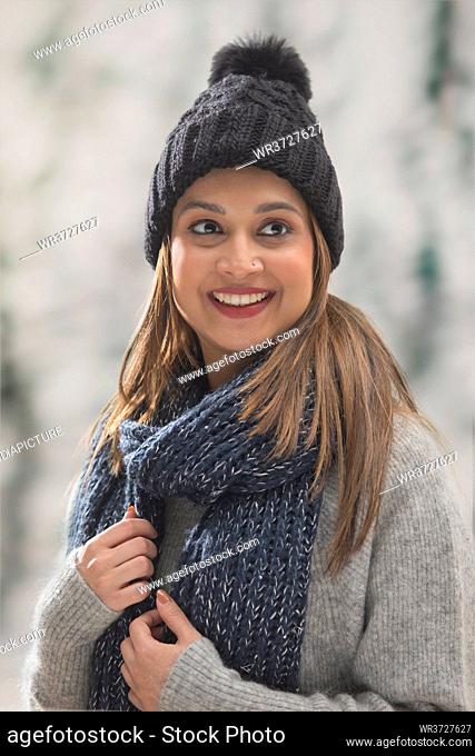PORTRAIT OF A HAPPY WOMAN DRESSED IN WOOLEN CLOTHES LOOKING AWAY AND SMILING