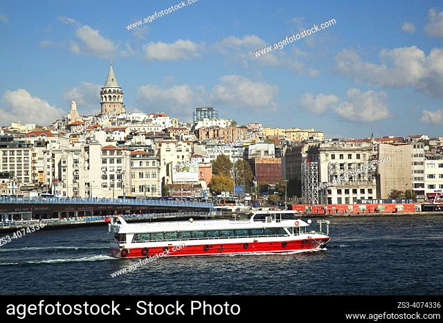 View of the Galata Tower with the Galata Bridge and a tour boat in the foreground in Galata village, a neighbourhood on the European side of the Bosphorus in...