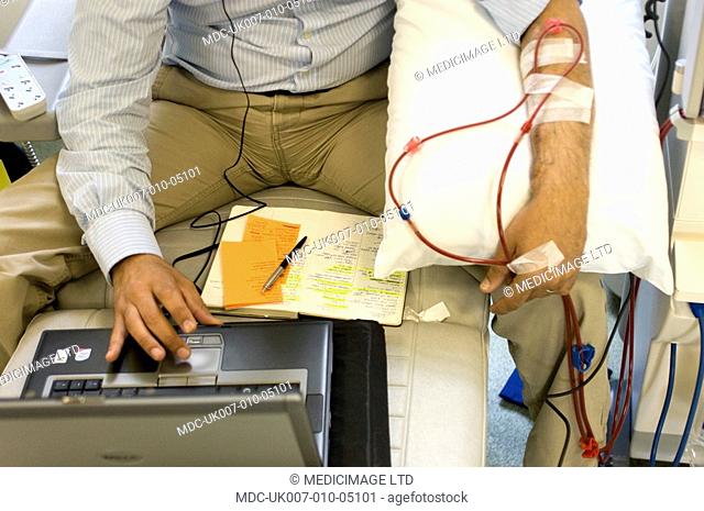 A kidney patient on his regular visit to the renal dialysis ward of a London hospital where he is connected to a hemodialysis machine which essentially cleans...