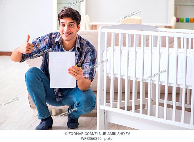 Young man assembling baby bed with instruction manual