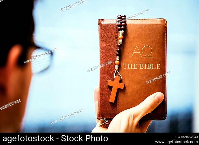 Young preacher is holding the holy bible, praying