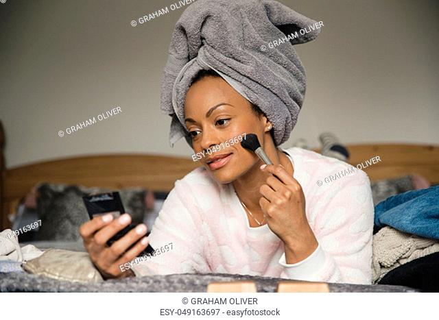 Mid adult mixed race woman applying make-up during her daily morning routine