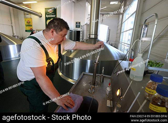 14 February 2023, Thuringia, Apolda: Brewer Ralf Cucinschi spindles the original wort at a control stand. The Apoldaer Vereinsbrauerei is a regional brewery