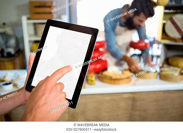 Staff using digital tablet at bakery counter