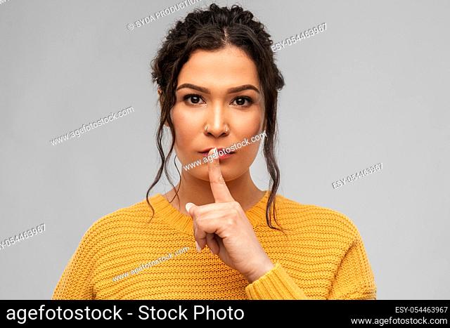 young woman with pierced nose making hush gesture