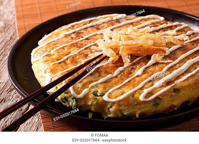 Japanese pizza: okonomiyaki on a plate close-up and chopsticks. horizontal
