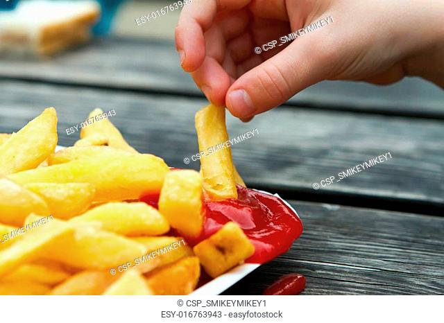child dipping a chip into tomato sauce