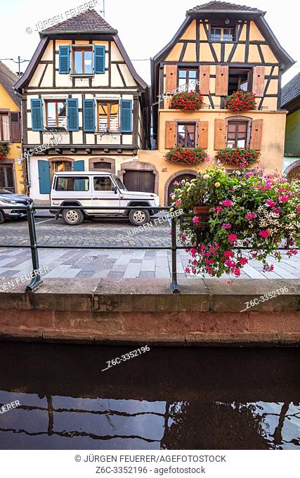 flower decorated brook and old timbered houses with carving, village Ribeauvillé, Alsace, France, location of the Wine Route