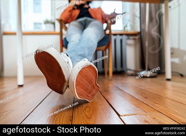 Young man with legs crossed over hardwood floor at home