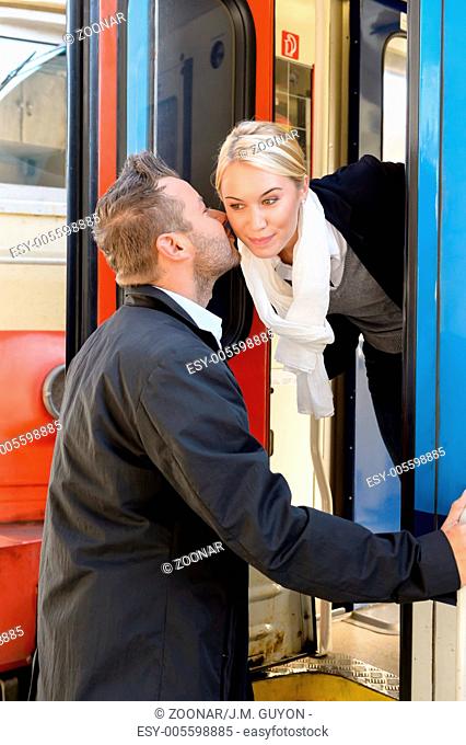 Man kissing woman goodbye on cheek train