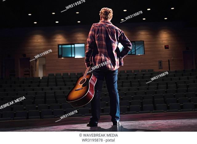 Man standing with guitar on stage