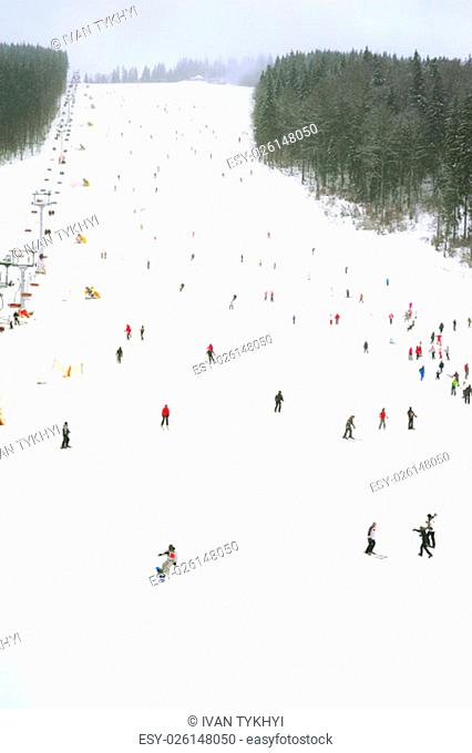 Skiers and snowboarders on a slope at sky resort during the heavy snowfall