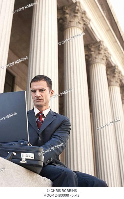 Lawyer using laptop outside courthouse