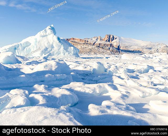 Icebergs in front of Appat Island, frozen into the sea ice of the Uummannaq fjord system during winter in the the north west of Greenland