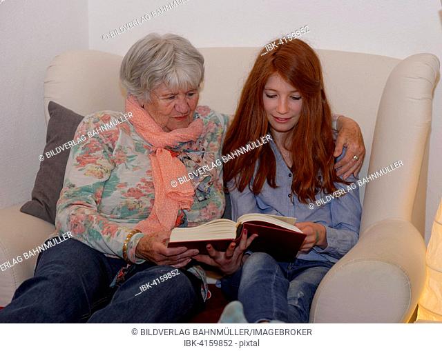 Granddaughter and grandmother reading a book together, Bavaria, Germany