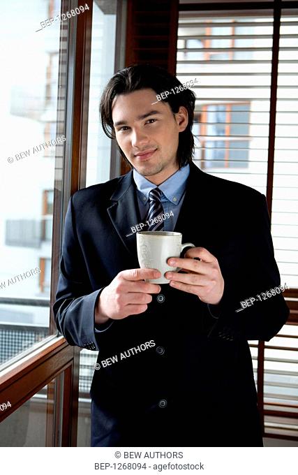 Man drinking coffee while looking out the window