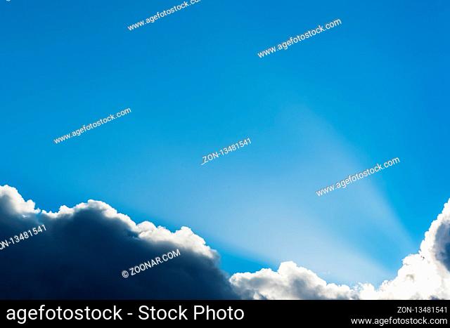 The sunbeam rises at the right edge of the cloud with a blue sky