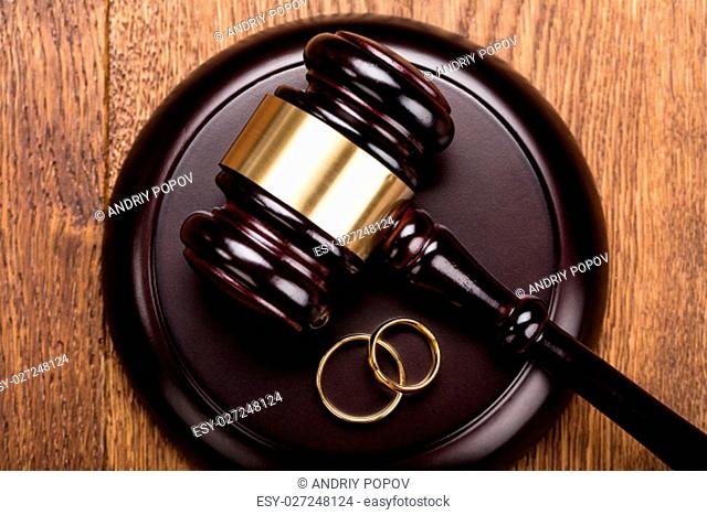 High Angle View Of Divorce Concept With Gavel And Wedding Rings At Wooden Desk