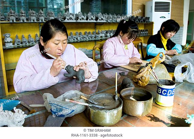 Women make clay figure souvenirs in factory, Xian, China