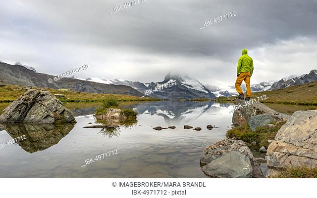 Hiker stands on rock, Lake Stellisee, behind Matterhorn, cloudy, Wallis, Switzerland, Europe