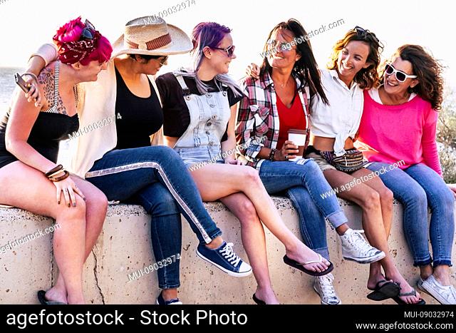 Group of young women sitting and enjoying the leisure outdoor activity together speaking and smiling with happiness - pink and violet hair for millennial...