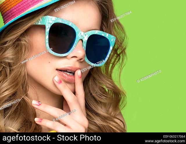 Bright cheerful girl in a summer hat, colorful make-up, curls and pink manicure. Beauty face. Photo taken in the studio