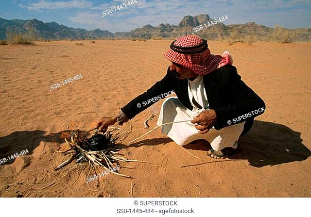 Bedouin man crouching near fire, Wadi Rum, Jordan