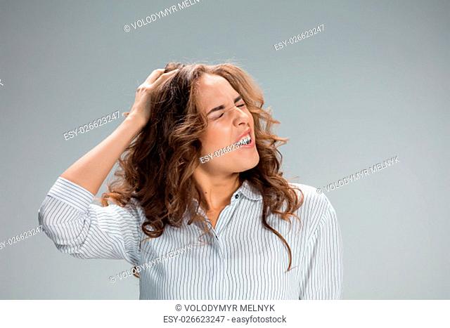 The young woman&#39;s portrait with pain emotions on gray background. Concept headache