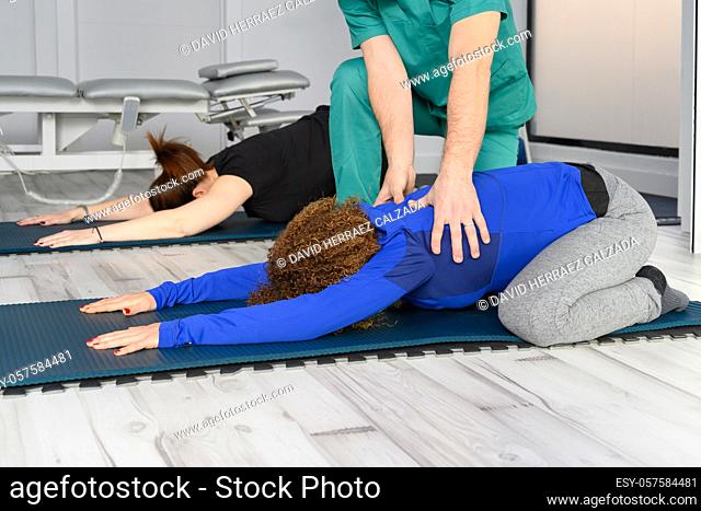 Woman exercising with therapist on yoga mat at clinic. High quality photo