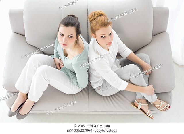 Unhappy young female friends not talking after argument on the couch