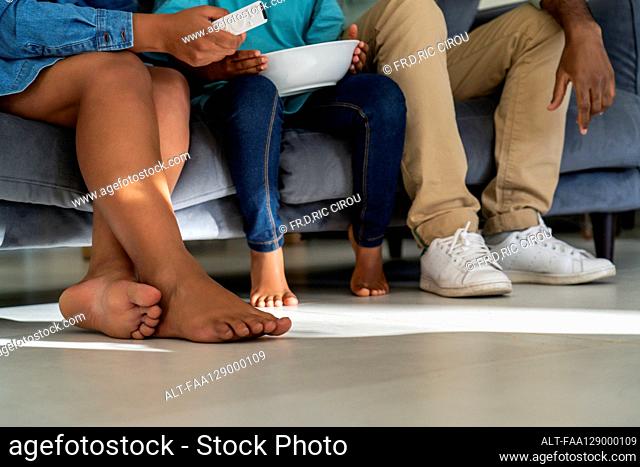 Family watching television together while sitting on sofa