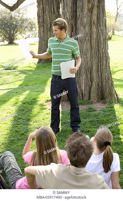 Park, man, young, stands, reading, students, sitting, listening, back view, series, people, teenagers, students, friends, schoolmates, school-colleagues