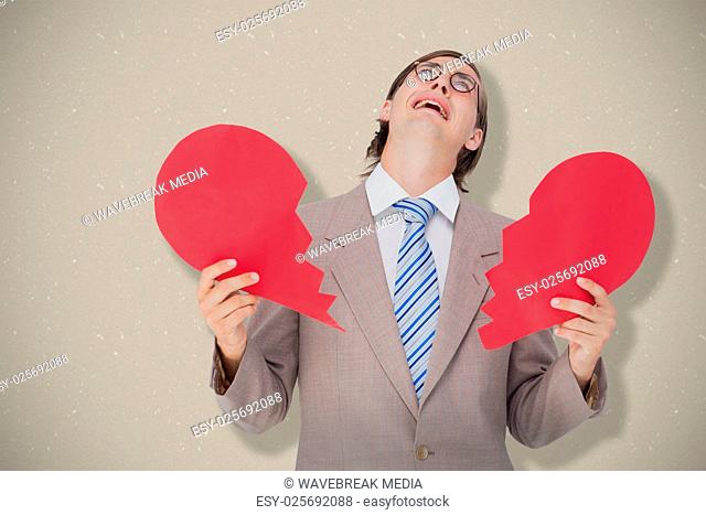 Composite image of geeky businessman crying and holding broken heart card