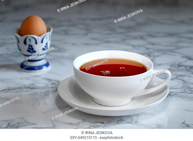 A cup of tea and a boiled egg in the background, breakfast time