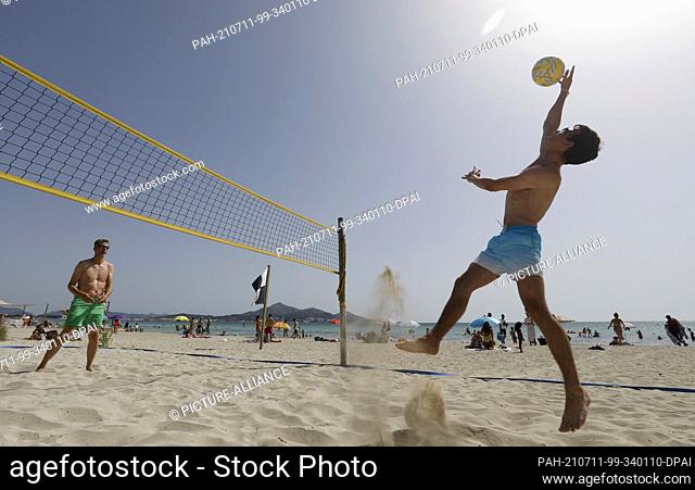 11 July 2021, Spain, -: Tourists Olli (r) and Birger from Rostock play volleyball on the beach of Playa de Muro in the north of Mallorca