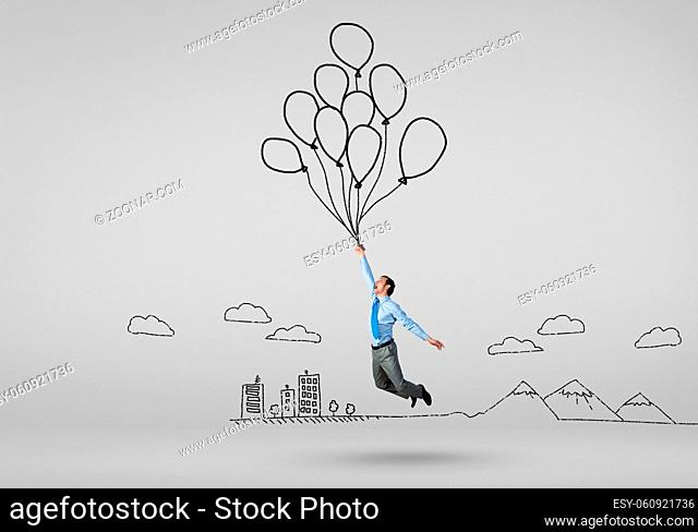 Young successful businessman flies on bunch of drawn balloons