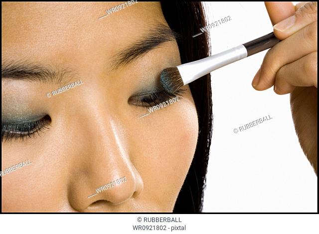 Closeup of woman applying eyeshadow with makeup brush